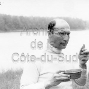 L&rsquo;abb&eacute; Maurice Proulx mange, pr&egrave;s d&rsquo;un lac, lors du tournage de En pays neufs en Abitibi