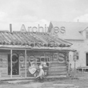 Famille sur la galerie d&rsquo;une maison en bois rond &agrave; Saint-Octave de l&rsquo;Avenir en Gasp&eacute;sie.