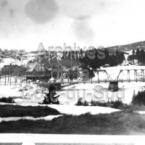 Vue du pont m&eacute;tallique de Saint-Pac&ocirc;me avec la partie ouest du village en arri&egrave;re-plan